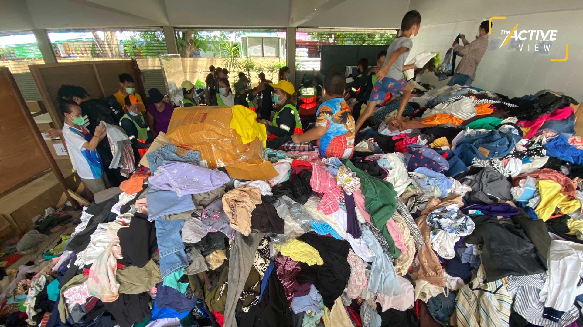 เสื้อผ้าจำนวนมาก จากผู้บริจาค ถูกนำมากองรวมกันไว้ใต้อาคารเรือนนอน รอส่งต่อให้กับผู้ประสบภัย และกระจายไปยังพื้นที่ที่มีความต้องการต่อไป