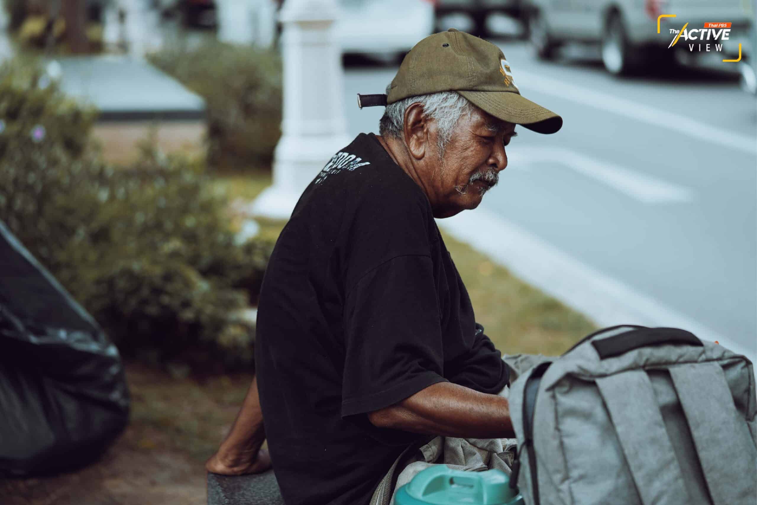 
“ลุงตุ๋ย” หรือ “มงคล” วัย 68 ปี นั่งอยู่อย่างโดดเดี่ยว ข้างกายของเขาเต็มไปด้วยสัมภาระ มีกระเป๋า 3 ใบ กระติกน้ำอีก 1 ใบ ในกระเป๋ามีของใช้ส่วนตัว สบู่ ยาสระผม ยาสีฟัน มีเสื่ออีกหนึ่งผืนไว้ปูนอน ที่เท้าขวาของลุงตุ๋ย เราสังเกตเห็นว่านิ้วเท้ามีลักษณะผิดรูป นี่อาจเป็นเหตุผลให้เขาเลือกมาใช้ชีวิต อยู่ข้างถนน 